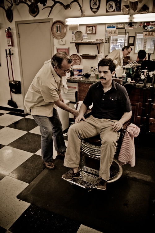 A man sitting on chair at barbershop.