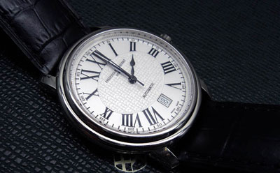 Round wrist watch with black leather straps.