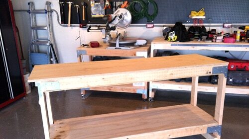 An all-purpose workbench in a garage with tools on it.