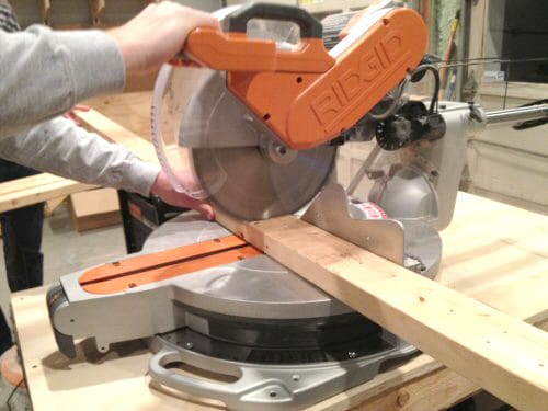 Man cutting wood piece with a miter saw. 