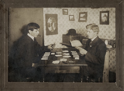 Vintage men playing cards at table with cigars. 