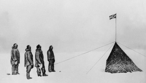 A black and white drawing of a group of people standing in the snow, achieving their goal at the South Pole.