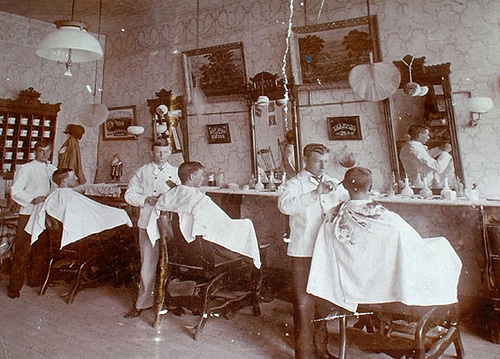 Vintage men getting hair cut at barbershop. 