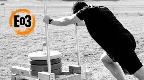 A man doing a push up on a DIY wooden platform.