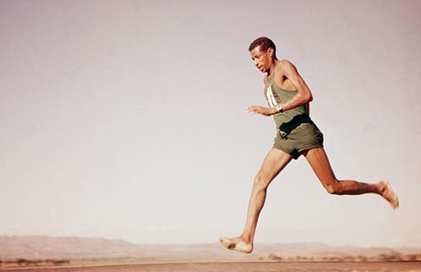 An old photo of a man running barefoot in the desert, accompanied by FAQ's.