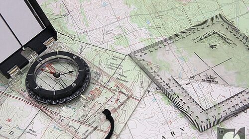 A compass on top of a topographic map.