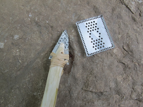 Vintage folding and pounding a small, thin piece of metal into another arrowhead-shaped point.