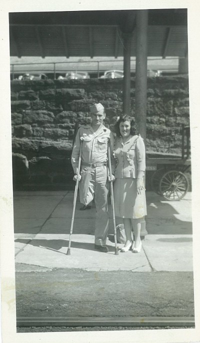 Vintage army man missing his leg standing with young lady.