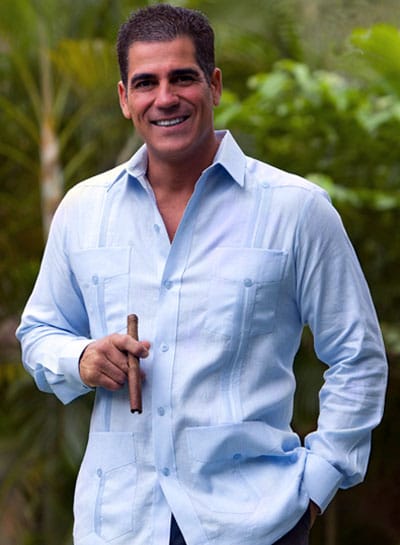 Man wearing oxford guayabera smoking cigar.