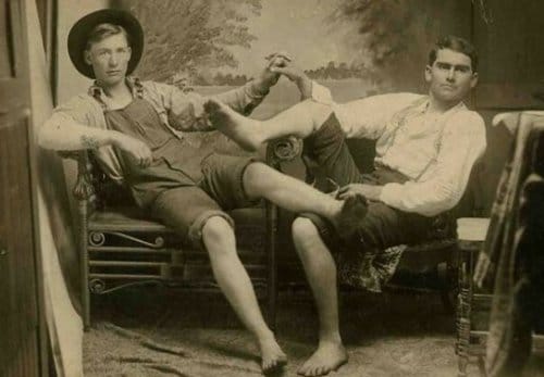 An old photo showing two men sitting on a chair, displaying their male affection.