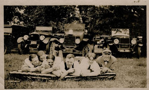 Vintage peoples are laying front of vehicles black and white photo illustration.