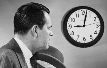 An importance-driven man in a suit keeping a punctual eye on a clock.