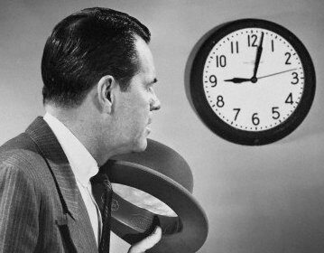 An importance-driven man in a suit keeping a punctual eye on a clock.