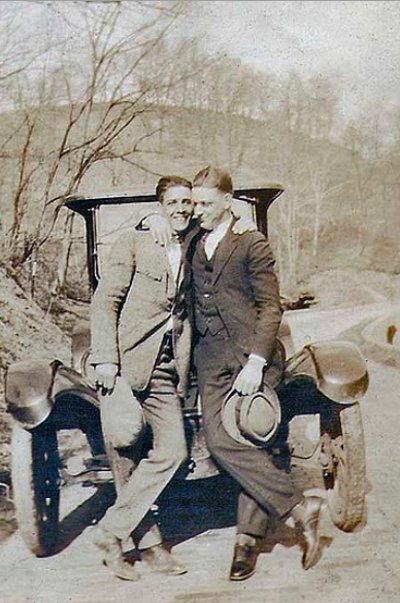 Vintage two men standing front of vehicle and holding hats black and white illustration.