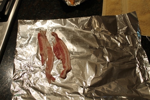 Vintage tear a strip of bacon in half and place on foil.