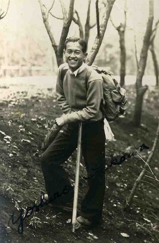 Vintage Asian man hiking outdoors having walking stick.