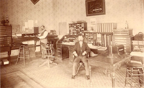 Vintage businessmen in large office at desks.