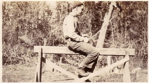 A man sitting on a strong fence.