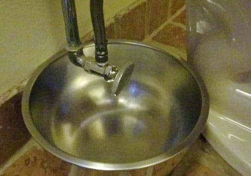 Draining water tank of toilet bowl into basin.