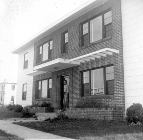 Vintage man standing in doorway of apartment building.