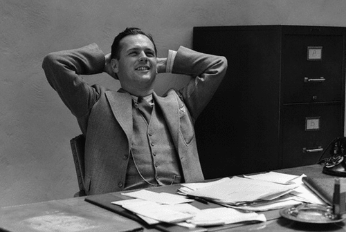 Vintage man businessman leaning back at desk satisfied.