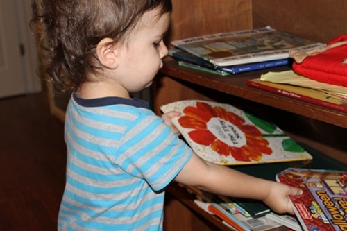 Young boy putting books away doing chores. 