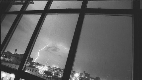 A captivating black and white photo capturing the awe-inspiring power of a lightning strike through a window.