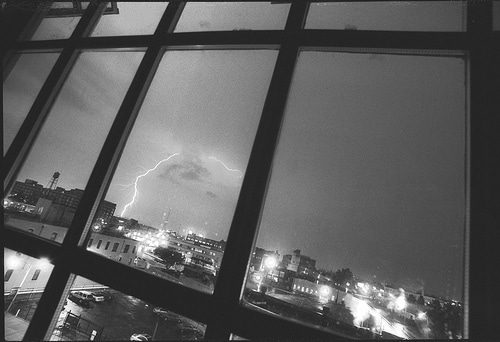 A captivating black and white photo capturing the awe-inspiring power of a lightning strike through a window.