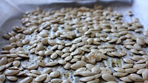 Seasoned roast pumpkin seeds on a baking sheet.