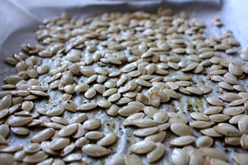 Seasoned roast pumpkin seeds on a baking sheet.