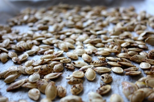 Roasted pumpkin seeds on baking sheet close up photo. 