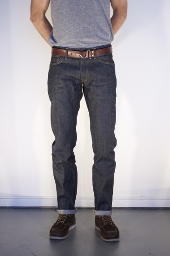 Fitted raw denim jeans rolled cuffs with boots leather belt.
