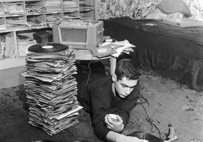 A man, passionate about vinyl record collecting, spins his favorite records as he lays on the floor with a vintage record player.