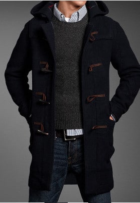Duffle coat unbuttoned over sweater and jeans. 