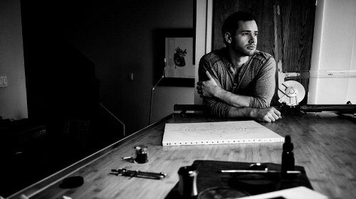 A black and white photo of a man sitting at a table, showcasing the artistry of a Master Penman.