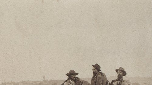 Three American South men proudly standing on a pile of logs, embodying manly honor.