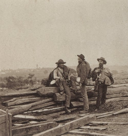 Three American South men proudly standing on a pile of logs, embodying manly honor.