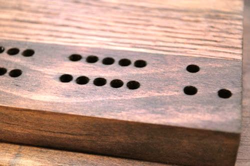 DIY wooden cribbage board having holes.