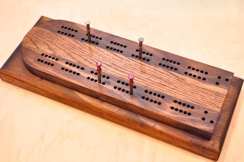 DIY wooden cribbage board having holes and nails in it.