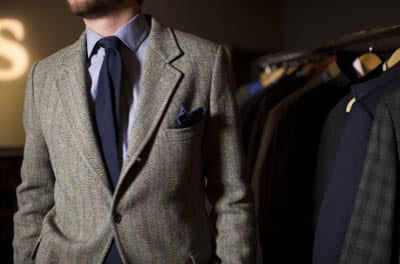 Male model wearing grey blazer blue tie button up shirt.