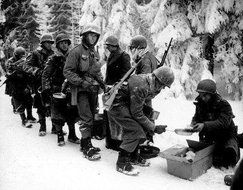 Vintage WW-II soldiers being served rations snowy forest. 