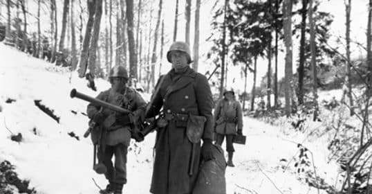 Soldiers trekking through snowy terrain during the Christmas 1944 military campaign.