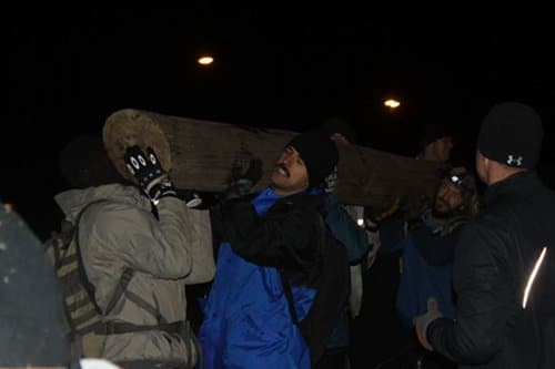 Man helping the people to carry a log.