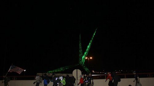 A group of people standing in front of a green light, ready to take on the GORUCK challenge.