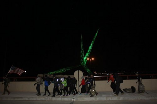 A group of people standing in front of a green light, ready to take on the GORUCK challenge.