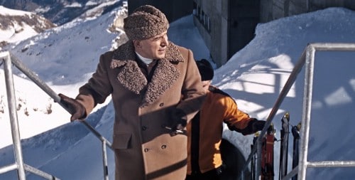 James Bond villain wearing astrakhan hat and brown overcoat. 