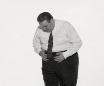 A black and white photo of a man chef standing on a scale and losing weight.