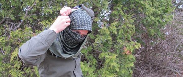 A man wearing a military-style balaclava in the woods.