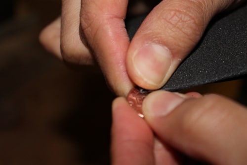 Using sandpaper cleaning on penny for diy charm bracelet. 