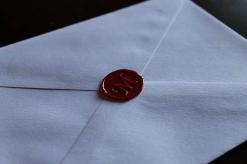 Red wax seal on envelope with M monogram. 